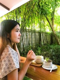 Portrait of woman sitting on table against trees