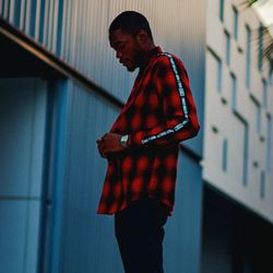 Side view of young man looking away against wall