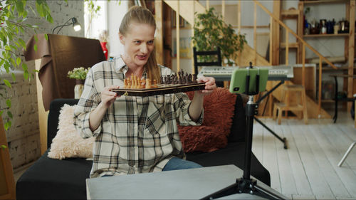 Woman holding chessboard at home