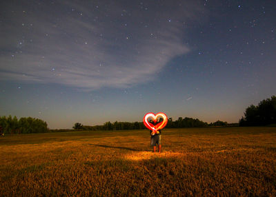 Couple making heart shape with wire wools on land at night