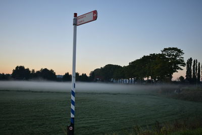 Information sign on field against clear sky at sunset