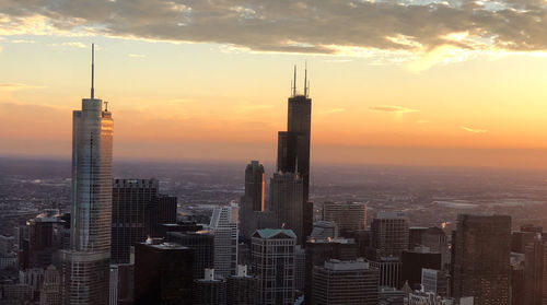 Modern buildings in city against sky during sunset