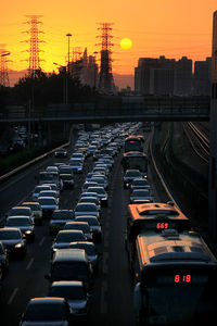Cars on road in city against sky during sunset