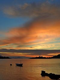 Silhouette boat in sea against sky during sunset