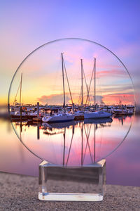 Sailboats moored in marina at sunset