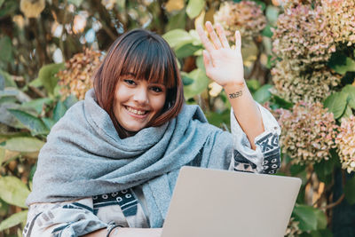 Portrait of young woman using laptop at park