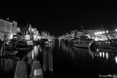 Boats moored in harbor at night