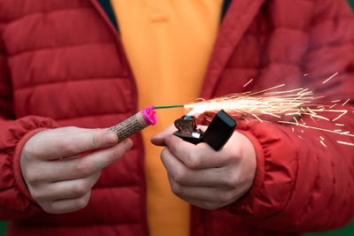 Midsection of person holding lighter and bomb