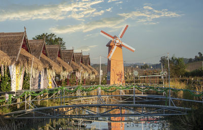 Traditional windmill by canal against sky