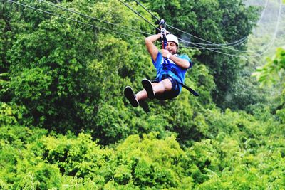 Full length of man hanging on rope in forest