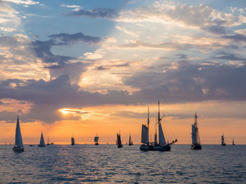 Sailboats sailing on sea against sky during sunset