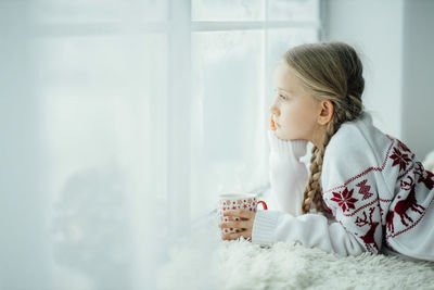 Side view of mother and daughter sitting on bed at home