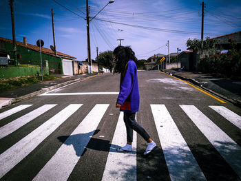 Side view of girl walking on road against sky