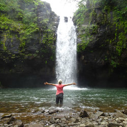 Man standing on rock against waterfall