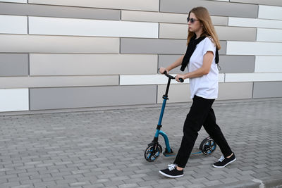 Portrait of young woman walking on footpath