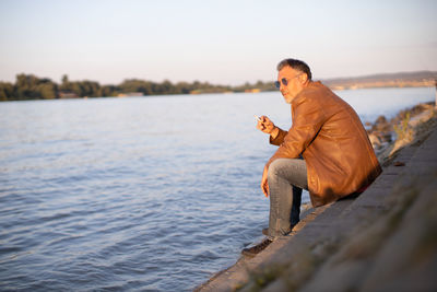 Lonely man sitting on the river bank