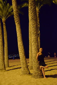 Full length of woman standing by tree at night