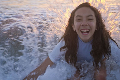 Portrait of smiling woman in sea during sunset