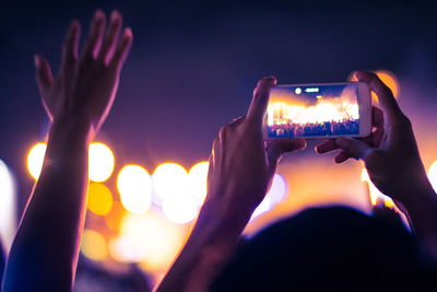 Close-up of hands photographing with smart phone at music concert