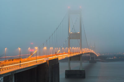 Suspension bridge over river during foggy weather