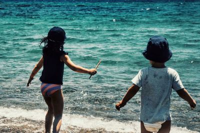 Rear view of siblings on shore at beach