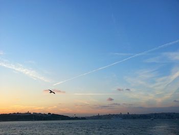 Scenic view of sea against vapor trails in sky