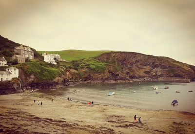 People on beach by mountain against sky