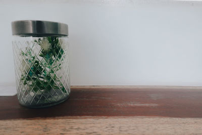 Close-up of glass jar on table against wall