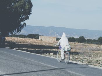 Rear view of woman on road against sky