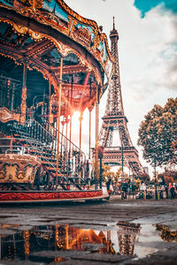 Ferris wheel in city against cloudy sky