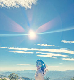 Woman standing against sky on sunny day