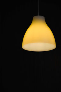 Yellow illuminated lamp against black background