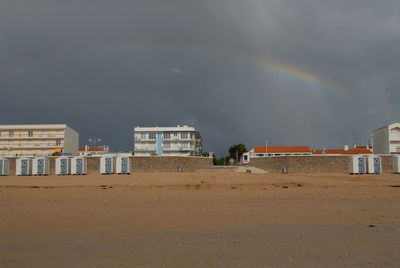 Scenic view of beach against rainbow in city