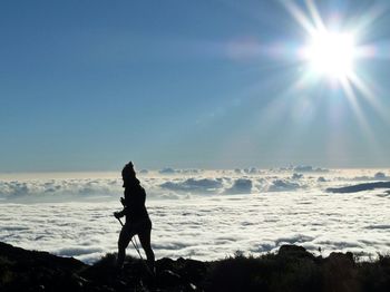 Woman hiking on mountain against sky during sunny day