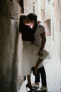 Side view of young couple kissing against wall