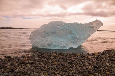 Ice on beach against sky during sunset