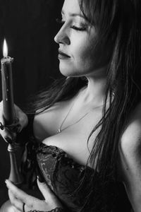 Close-up of young woman holding lit candle