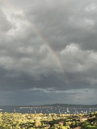 Rainbow over city against cloudy sky