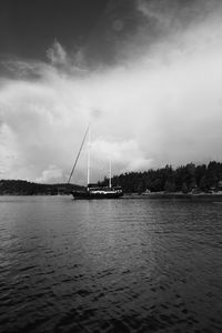 Sailboat sailing in sea against cloudy sky