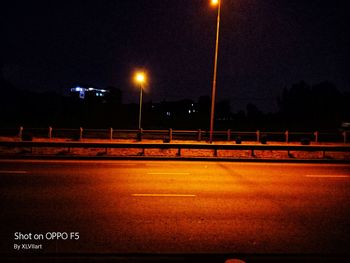Illuminated road against sky at night
