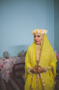 Bride wearing traditional clothing looking away at home