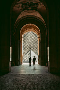 Rear view of people walking in corridor of building