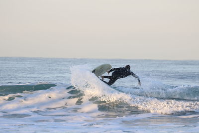 Man surfing in sea against clear sky