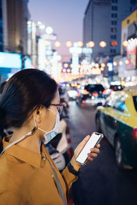 Woman holding mobile phone in city