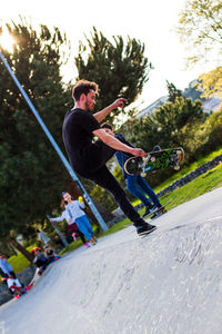 Young man skateboarding on tree against sky