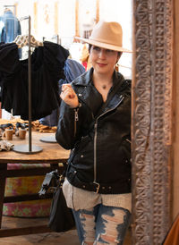 Smiling woman wearing hat looking away at boutique