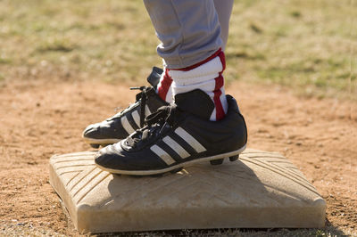 Boys baseball cleats standing on top of a base