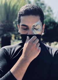 Close-up of young man with eye paint covering face with turtleneck t-shirt