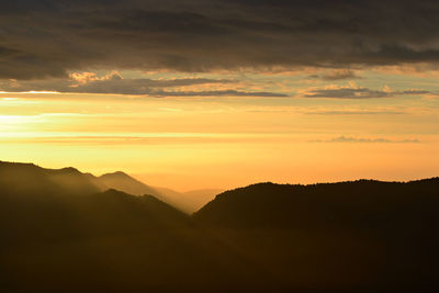 Scenic view of silhouette mountains against orange sky