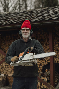 Portrait of man holding hat while standing outdoors